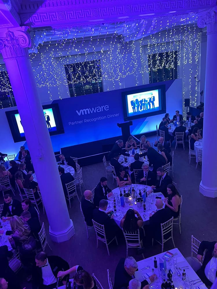 People at an events dinner party with a stage in the background