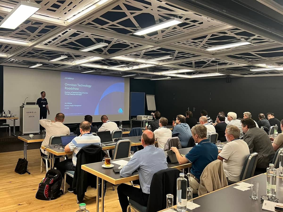 A speaker talking in front of a group of people who are sitting at desks